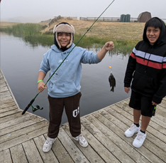 two boys, one has a fish on the line