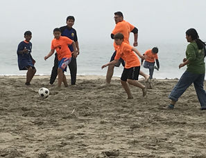group playing soccer on beach
