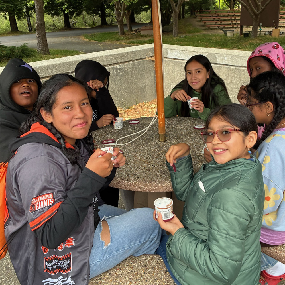 Counselors sitting at a small table eating ice cream
